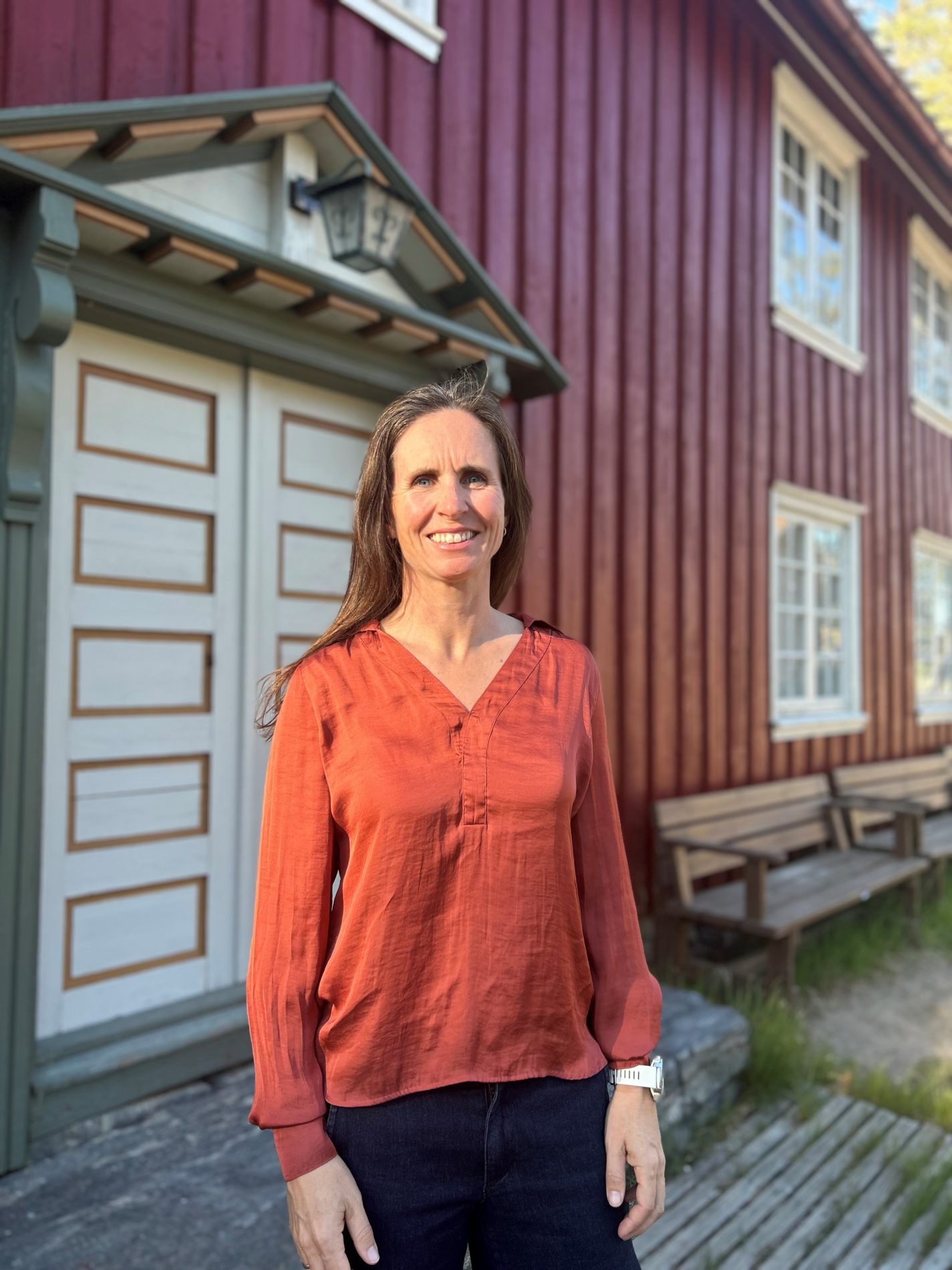 Smilende kvinne står foran en fargerik bygning.